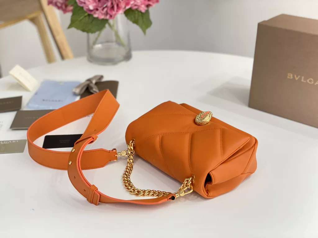 Bulgari BVLGARI-Spring Summer 2022 Orange<br>The color from the summer ocean (22㎝)<br>The Serpenti Cabochon quilted bag is the highlight of BVLGARI this summer - firstly, the classic quilted pattern is enlarged in proportion, the bag looks full and geometric; and then a white lac thick chain is added to decorate, the rugged style is modern. The bag is made of orange stones and imported first layer calf leather, decorated with delicate orange onyx snake scales and gold-plated snake head clasp with mother-of-pearl snake scales in the center, embellished with red enamel eyes.<br>291089# Size: 22.5<em>15</em>10cm<br>291085# Size: 18<em>12</em>8cm