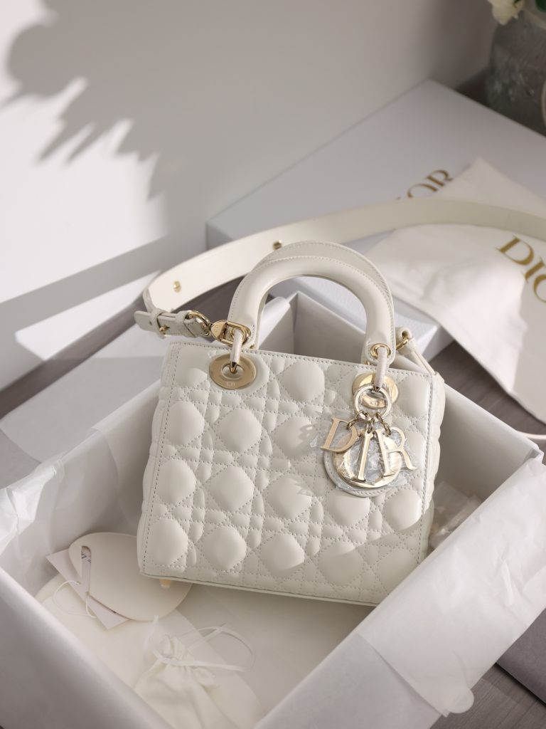 Small LADY DIOR handbag<br>White sheepskin rattan plaid<br>Four compartments Dior bag white sheepskin gold buckle<br>Exclusive channel goods debut with 7 exclusive badges<br>Size information: 20 x 17 x 8 cm<br>This Lady Dior My ABCDior clutch focuses on Dior's deep insight into elegance and beauty.<br>Crafted from white lamb leather with striking quilted details in a vine check pattern, its chic and elegant design is timeless.<br>The light gold finish metal D.I.O.R. charm is an elegant touch.<br>The small, chic design features a shoulder strap that can be adorned with a badge to show off your personality, and can be carried or slung.<br>The wide, adjustable shoulder strap includes three badges for a personalized look. A total of six badges are available for decoration.<br>Interior zippered pocket<br>Additional embroidered straps available<br>Dust bag included<br>Comes in exclusive counter packaging