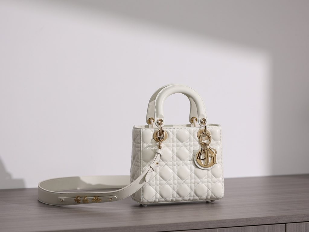 Small LADY DIOR handbag<br>White sheepskin rattan plaid<br>Four compartments Dior bag white sheepskin gold buckle<br>Exclusive channel goods debut with 7 exclusive badges<br>Size information: 20 x 17 x 8 cm<br>This Lady Dior My ABCDior clutch focuses on Dior's deep insight into elegance and beauty.<br>Crafted from white lamb leather with striking quilted details in a vine check pattern, its chic and elegant design is timeless.<br>The light gold finish metal D.I.O.R. charm is an elegant touch.<br>The small, chic design features a shoulder strap that can be adorned with a badge to show off your personality, and can be carried or slung.<br>The wide, adjustable shoulder strap includes three badges for a personalized look. A total of six badges are available for decoration.<br>Interior zippered pocket<br>Additional embroidered straps available<br>Dust bag included<br>Comes in exclusive counter packaging