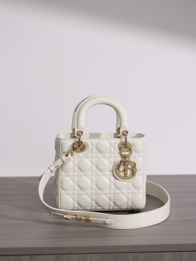 Small LADY DIOR handbag<br>White sheepskin rattan plaid<br>Four compartments Dior bag white sheepskin gold buckle<br>Exclusive channel goods debut with 7 exclusive badges<br>Size information: 20 x 17 x 8 cm<br>This Lady Dior My ABCDior clutch focuses on Dior's deep insight into elegance and beauty.<br>Crafted from white lamb leather with striking quilted details in a vine check pattern, its chic and elegant design is timeless.<br>The light gold finish metal D.I.O.R. charm is an elegant touch.<br>The small, chic design features a shoulder strap that can be adorned with a badge to show off your personality, and can be carried or slung.<br>The wide, adjustable shoulder strap includes three badges for a personalized look. A total of six badges are available for decoration.<br>Interior zippered pocket<br>Additional embroidered straps available<br>Dust bag included<br>Comes in exclusive counter packaging