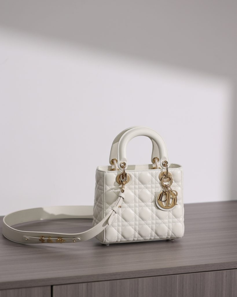 Small LADY DIOR handbag<br>White sheepskin rattan plaid<br>Four compartments Dior bag white sheepskin gold buckle<br>Exclusive channel goods debut with 7 exclusive badges<br>Size information: 20 x 17 x 8 cm<br>This Lady Dior My ABCDior clutch focuses on Dior's deep insight into elegance and beauty.<br>Crafted from white lamb leather with striking quilted details in a vine check pattern, its chic and elegant design is timeless.<br>The light gold finish metal D.I.O.R. charm is an elegant touch.<br>The small, chic design features a shoulder strap that can be adorned with a badge to show off your personality, and can be carried or slung.<br>The wide, adjustable shoulder strap includes three badges for a personalized look. A total of six badges are available for decoration.<br>Interior zippered pocket<br>Additional embroidered straps available<br>Dust bag included<br>Comes in exclusive counter packaging