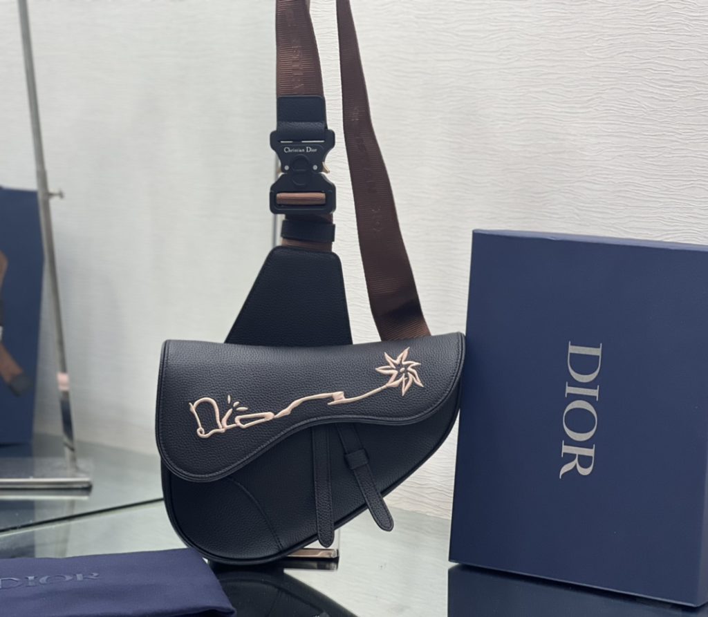 This saddle bag comes from the exclusive co-branded series of Dior and CACTUS JACK. Made of black grain cow leather, embroidered with CACTUS JACK DIOR logo to enhance style. With magnetic flap and hidden zipper closure, it can safely store all kinds of daily necessities. With adjustable 