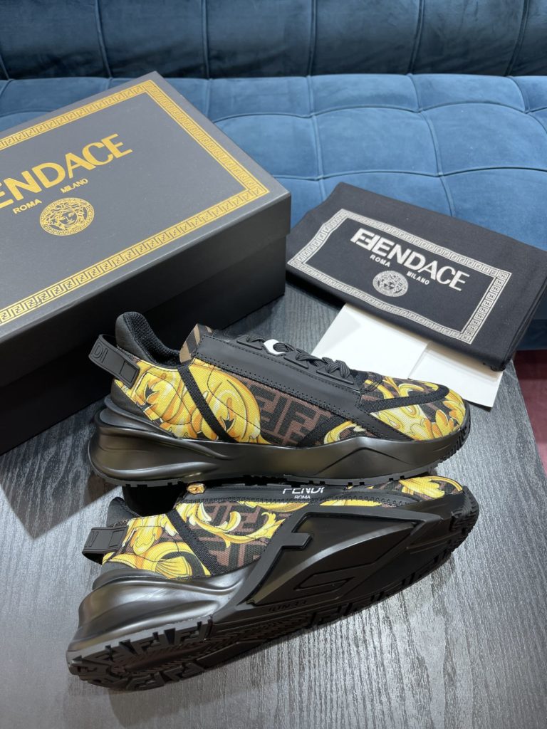 Versace by Fendi pedals sneakers with elastic laces and elastic inserts. The wavy sole is engraved with the word F. Embossed Fendi Flow on the heel. FF nylon with black and gold baroque scarf print. Lycra with FF pattern ® Tongue and Versace Medusa safety pin brooch shaped tab. Lightweight black rubber sole with diagonal F details. Made in Italy Size 39-44 (customized at 38.45)