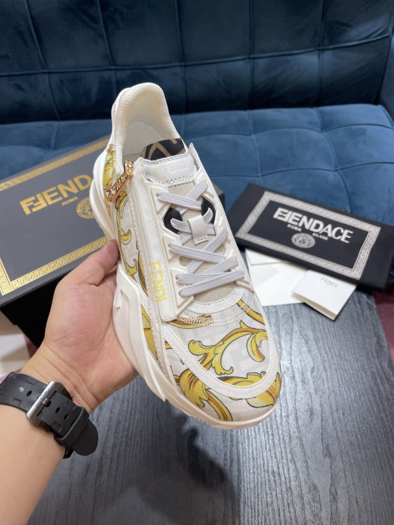 Versace by Fendi pedals sneakers with elastic laces and elastic inserts. The wavy sole is engraved with the word F. Embossed Fendi Flow on the heel. FF nylon with black and gold baroque scarf print. Lycra with FF pattern ® Tongue and Versace Medusa safety pin brooch shaped tab. Lightweight black rubber sole with diagonal F details. Made in Italy Size 39-44 (customized at 38.45)