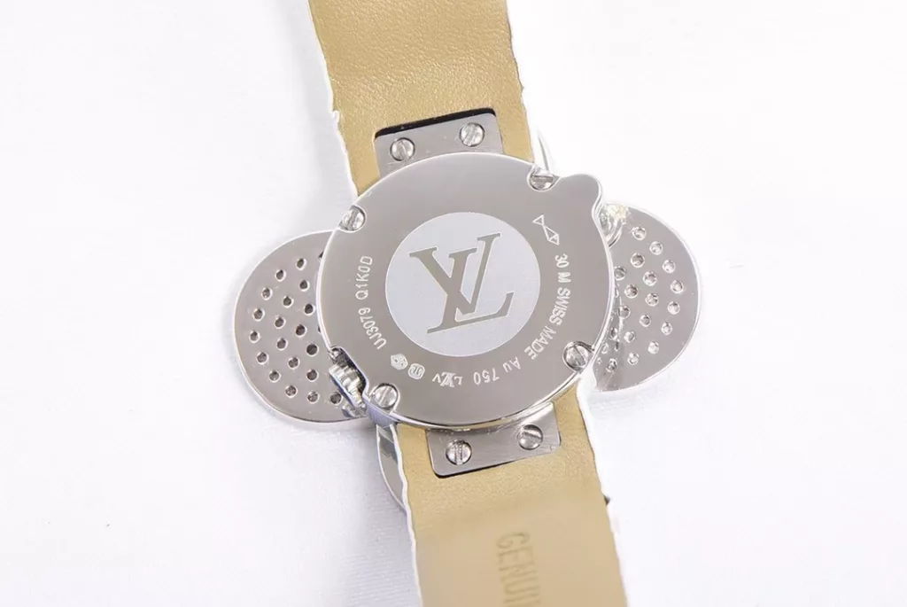 Louis Vuitton Women's Watch Vivienne Bijou Secret, Vivienne Mascot Collection Movement: Quartz. Functions: hour and minute display. Case: 18-carat white gold, 18-carat pink gold, 18-carat yellow gold with diamonds. Diameter: 34 mm. Anti-reflective sapphire crystal. Water-resistant to 30 m. For the first time, LOUIS VUITTON has incorporated its mascot, Vivienne, into the world of watchmaking, with the brave and charming Vivienne doll, dressed in diamond-embellished gold, to create a unique ladies' watch: the Vivienne Bijou Secret. Vivienne's face is movable, covering or revealing the 21 mm white gold case between rotations. The dial, appliquéd with white mother-of-pearl, is adorned with a graceful signature Monogram motif and set with diamond hour markers. The watch is currently available on four straps in red, black, green and white leather.