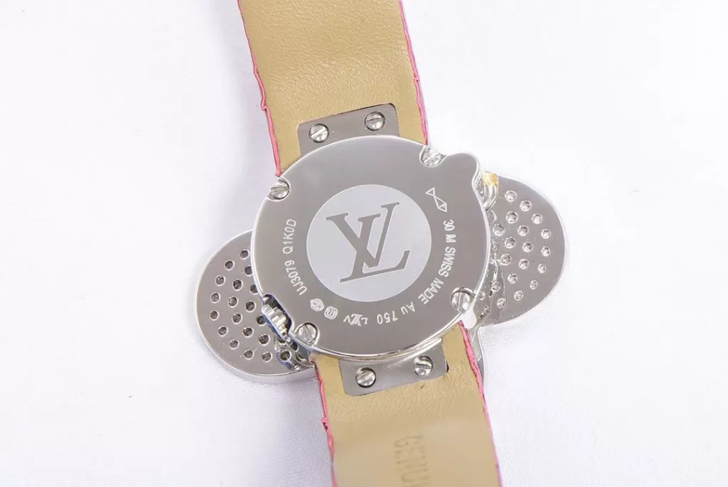 Louis Vuitton Women's Watch Vivienne Bijou Secret, Vivienne Mascot Collection Movement: Quartz. Functions: hour and minute display. Case: 18-carat white gold, 18-carat pink gold, 18-carat yellow gold with diamonds. Diameter: 34 mm. Anti-reflective sapphire crystal. Water-resistant to 30 m. For the first time, LOUIS VUITTON has incorporated its mascot, Vivienne, into the world of watchmaking, with the brave and charming Vivienne doll, dressed in diamond-embellished gold, to create a unique ladies' watch: the Vivienne Bijou Secret. Vivienne's face is movable, covering or revealing the 21 mm white gold case between rotations. The dial, appliquéd with white mother-of-pearl, is adorned with a graceful signature Monogram motif and set with diamond hour markers. The watch is currently available on four straps in red, black, green and white leather.