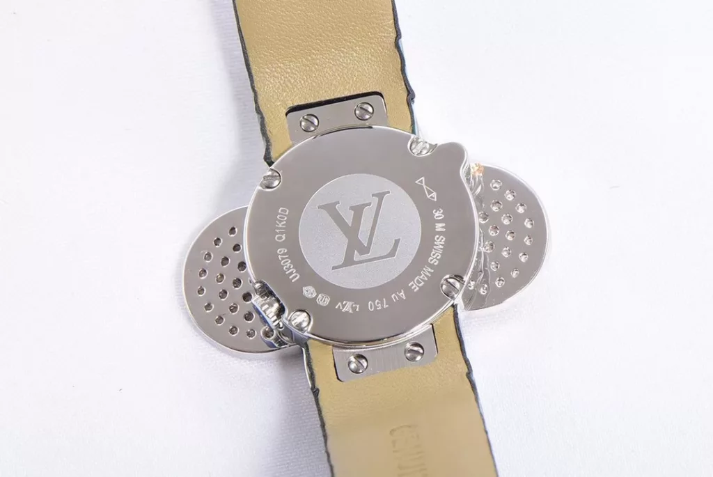 LOUIS VUITTON VIVIENNE BIJOU SECRET Mascot Movement: Quartz Movement Functions: Hours and minutes Case: 18K white gold, 18K pink gold, 18K yellow gold with diamonds Case diameter: 34 mm Anti-reflective sapphire Water-resistant to 30 metres This year, for the first time, LOUIS VUITTON is bringing its mascot, Vivienne, into the world of watchmaking with the Vivienne Bijou Secret. This year, for the first time, LOUIS VUITTON has incorporated the Vivienne doll into the world of watchmaking, with the brave and charming Vivienne doll in a gold dress embellished with diamonds, to create a unique ladies' watch: the Vivienne Bijou Secret. Vivienne's face is movable and will cover or reveal the 21 mm white gold case between rotations. The white mother-of-pearl appliquéd dial is decorated with the graceful signature Monogram motif and set with diamond hour markers. The watch is currently available on four straps in red, black, green and white leather.