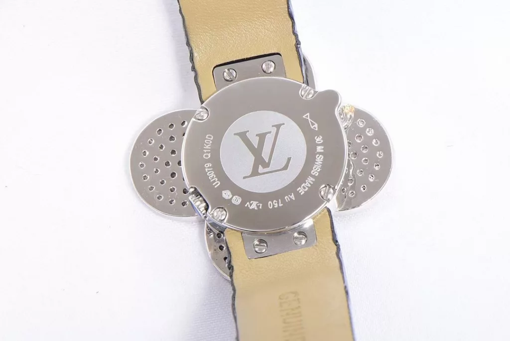 LOUIS VUITTON VIVIENNE BIJOU SECRET Mascot Movement: Quartz Movement Functions: Hours and minutes Case: 18K white gold, 18K pink gold, 18K yellow gold with diamonds Case diameter: 34 mm Anti-reflective sapphire Water-resistant to 30 metres This year, for the first time, LOUIS VUITTON is bringing its mascot, Vivienne, into the world of watchmaking with the Vivienne Bijou Secret. This year, for the first time, LOUIS VUITTON has incorporated the Vivienne doll into the world of watchmaking, with the brave and charming Vivienne doll in a gold dress embellished with diamonds, to create a unique ladies' watch: the Vivienne Bijou Secret. Vivienne's face is movable and will cover or reveal the 21 mm white gold case between rotations. The white mother-of-pearl appliquéd dial is decorated with the graceful signature Monogram motif and set with diamond hour markers. The watch is currently available on four straps in red, black, green and white leather.