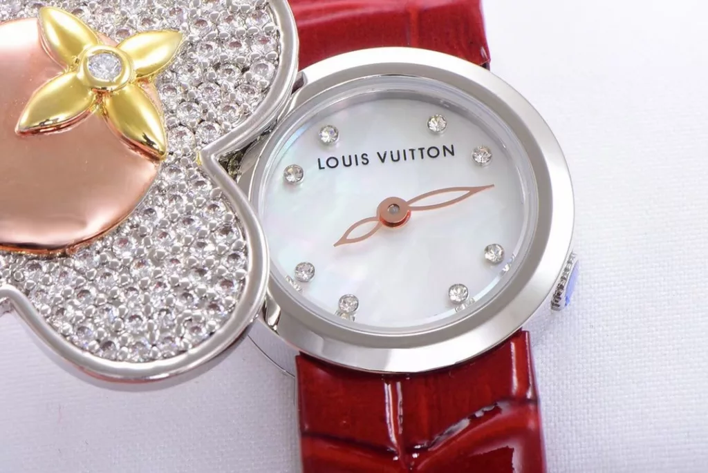 LOUIS VUITTON VIVIENNE BIJOU SECRET Mascot Movement: Quartz Movement Functions: Hours and minutes Case: 18K white gold, 18K pink gold, 18K yellow gold with diamonds Case diameter: 34 mm Anti-reflective sapphire Water-resistant to 30 metres This year, for the first time, LOUIS VUITTON is bringing its mascot, Vivienne, into the world of watchmaking with the Vivienne Bijou Secret. This year, for the first time, LOUIS VUITTON has incorporated the Vivienne doll into the world of watchmaking, with the brave and charming Vivienne doll in a gold dress embellished with diamonds, to create a unique ladies' watch: the Vivienne Bijou Secret. Vivienne's face is movable and will cover or reveal the 21 mm white gold case between rotations. The white mother-of-pearl appliquéd dial is decorated with the graceful signature Monogram motif and set with diamond hour markers. The watch is currently available on four straps in red, black, green and white leather.