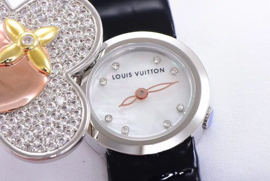 LOUIS VUITTON VIVIENNE BIJOU SECRET Mascot Movement: Quartz Movement Functions: Hours and minutes Case: 18K white gold, 18K pink gold, 18K yellow gold with diamonds Case diameter: 34 mm Anti-reflective sapphire Water-resistant to 30 metres This year, for the first time, LOUIS VUITTON is bringing its mascot, Vivienne, into the world of watchmaking with the Vivienne Bijou Secret. This year, for the first time, LOUIS VUITTON has incorporated the Vivienne doll into the world of watchmaking, with the brave and charming Vivienne doll in a gold dress embellished with diamonds, to create a unique ladies' watch: the Vivienne Bijou Secret. Vivienne's face is movable and will cover or reveal the 21 mm white gold case between rotations. The white mother-of-pearl appliquéd dial is decorated with the graceful signature Monogram motif and set with diamond hour markers. The watch is currently available on four straps in red, black, green and white leather.