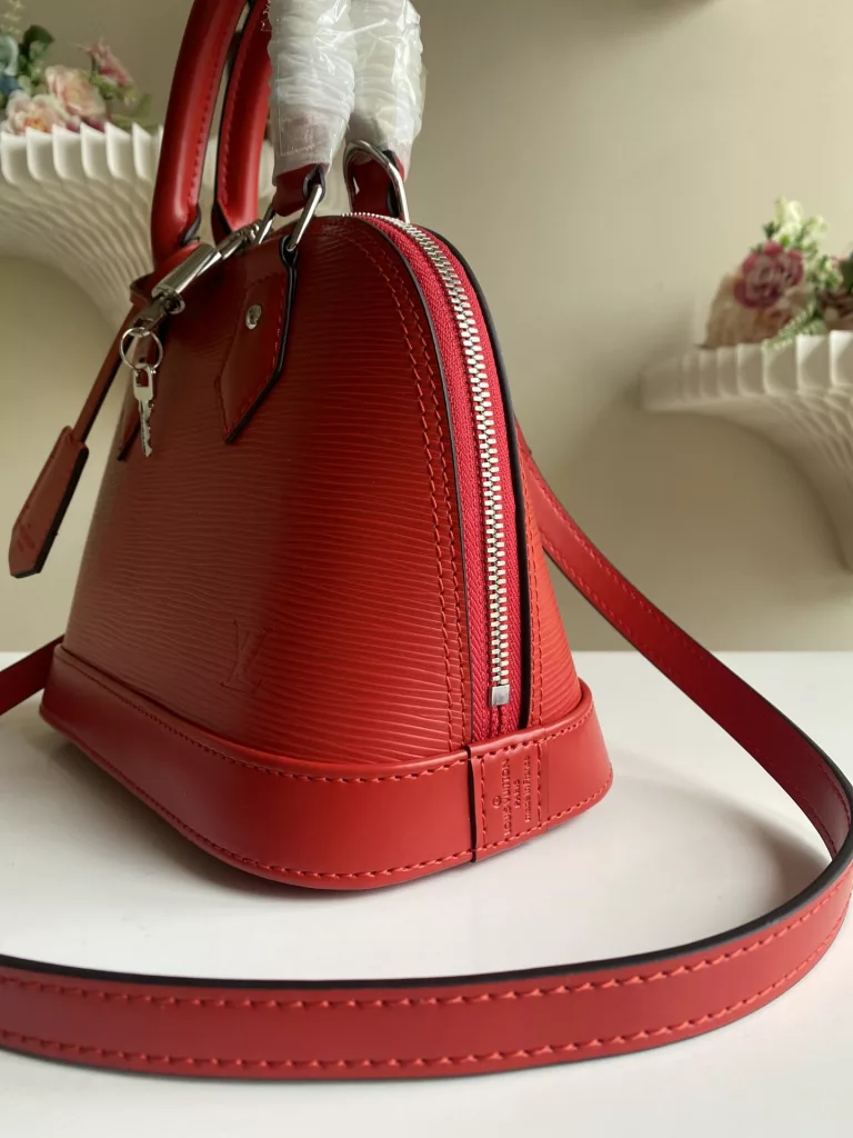 The top-level original ALMA BB handbag M40301 Carmine Red This Alma BB handbag M40302 M80862 presents a classic configuration in Epi grain leather, incorporating iconic elements such as a padlock, hand sewn Toron handle, and keycase. Removable shoulder straps for shoulder to shoulder or crossbody. Size: 23.5 * 17.5 * 11.5 cm