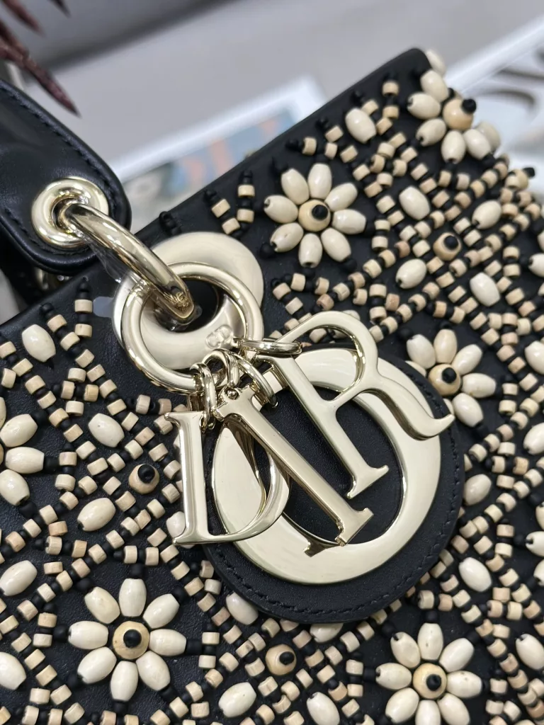 Lady D-Joy's horizontally embroidered black wooden beads, with imported lamb tendons inside, and the handbag are a brand new item of this season, fully demonstrating Dior's profound insight into elegance and beauty. Crafted with leather and embroidered with beads to create iconic patterns, the stylish and elegant design is timeless. Paired with gold faced metal 