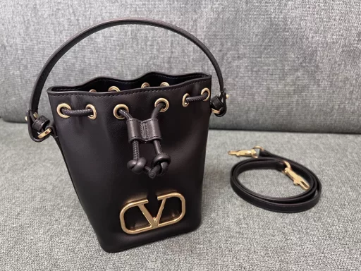 VALENTINO GARAVANIVLOGO SIGNATURE soft lambskin mini bucket bag. Thanks to the detachable shoulder strap and handle design, this mini handbag can be carried on the shoulder, crossbody or by hand at will.