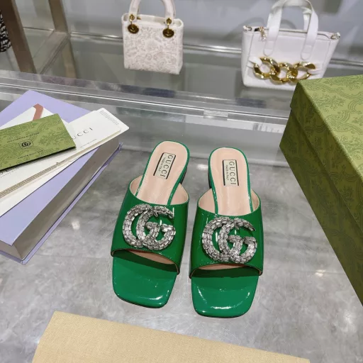 The crystal-embellished Double G-shaped accessory brings a modern twist to a range of women's shoes. On this pair of slides, the dazzling accessory is a striking addition to the shoe. Crafted in ivory patent leather, it is set on a leather sole to complete the design.