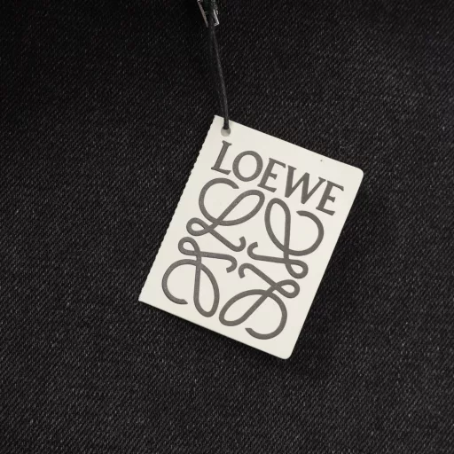 Loewe denim embroidered jeansUsing compact double-core yarn, laser-cut Anagram on the knees, classic LOEWE leather label, laser-cut, manually unpacked, laid flat to make laser-cut Anagram pattern, then manually patched inside and finally manually sewn on, expensive labor, high loss, low daily output, imported special machine infrared positioning, washing and color frying process, priority is given to special desizing agent, then the fabric is soaked in it to be evenly sizing before rinsing, loose version